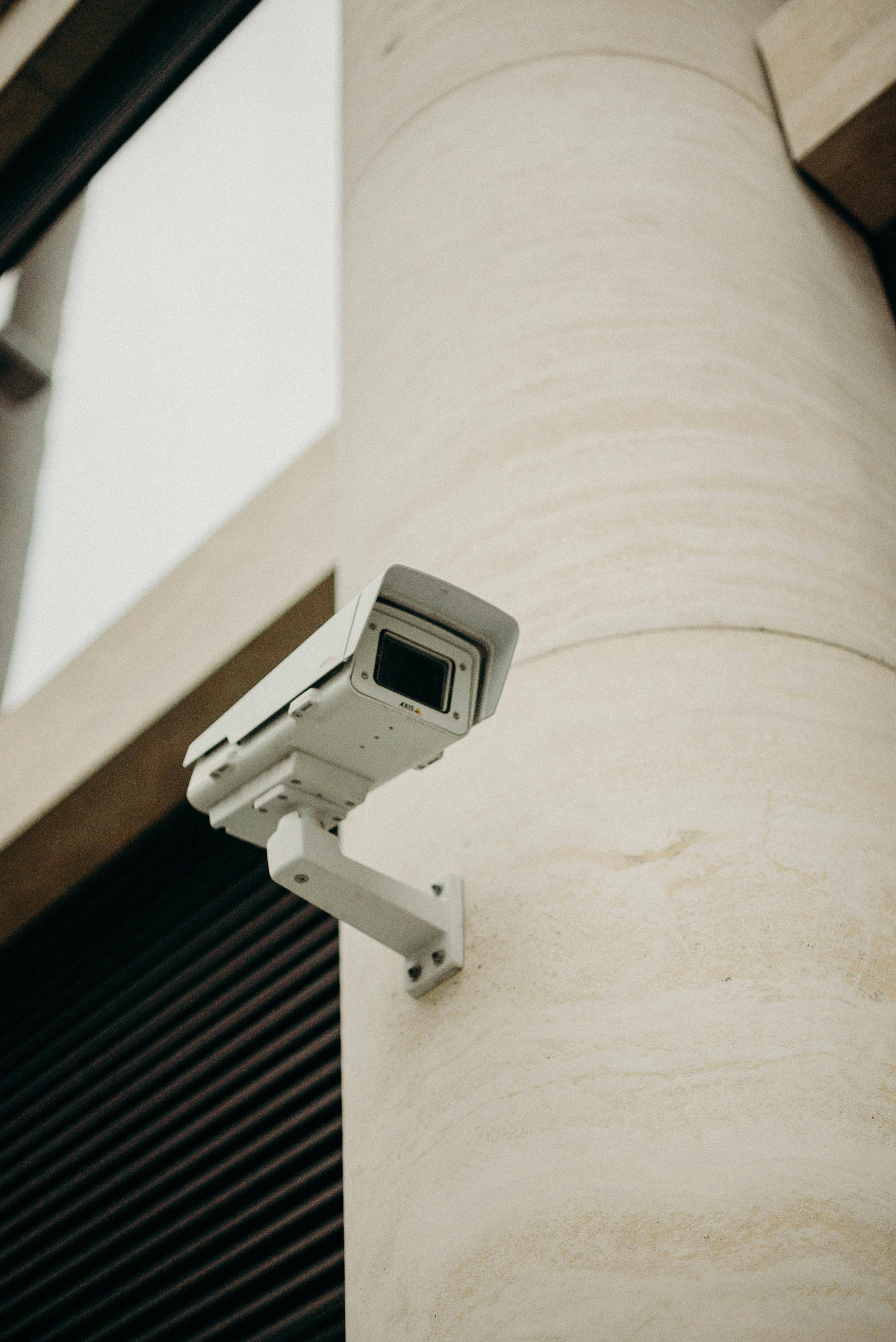 White Axis network bullet camera on a travertine stone pillar with articulating arm.